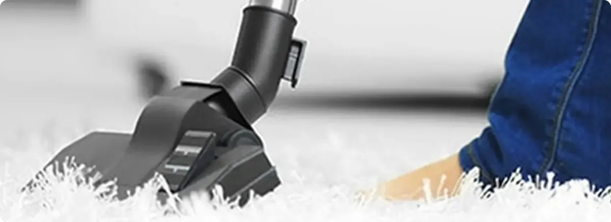 Close-up of a professional vacuuming a white carpet in Nedrow.